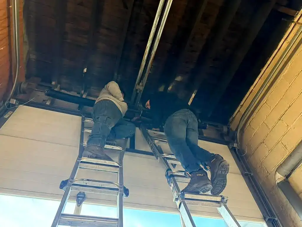 Both technicians up on the ladders for a track set