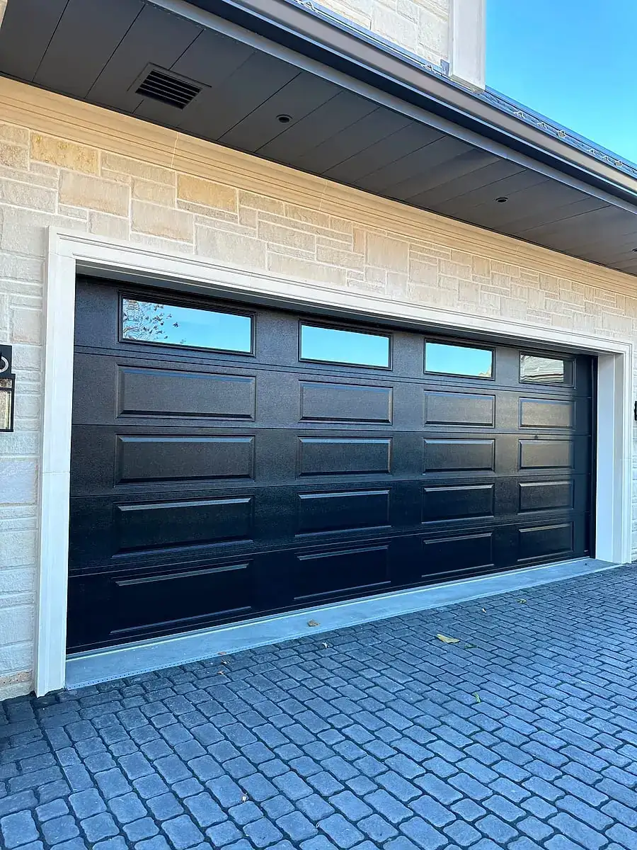 Black flush door with a top window row on a light-brick two-car garage