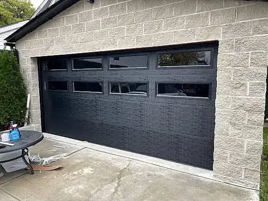Black modern door, four-window row, stone-front garage